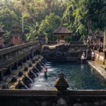 Intricate stone carved waterspouts gushing crystal clear holy spring water at Tirta Empul Temple