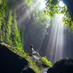 Visitors walking through shallow canyon river leading to Tukad Cepung Waterfall Bali