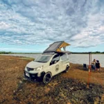 CAMPERVAN - EN - Home 27 East Bali Campervan di tepi pantai saat sunset dengan pasangan duduk santai di depan mobil