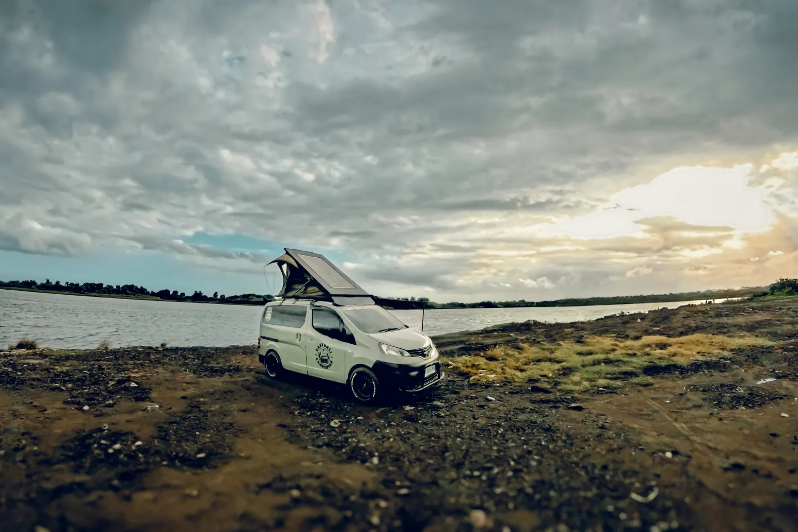 Campervan car parked under palm trees with ocean view in Bali.