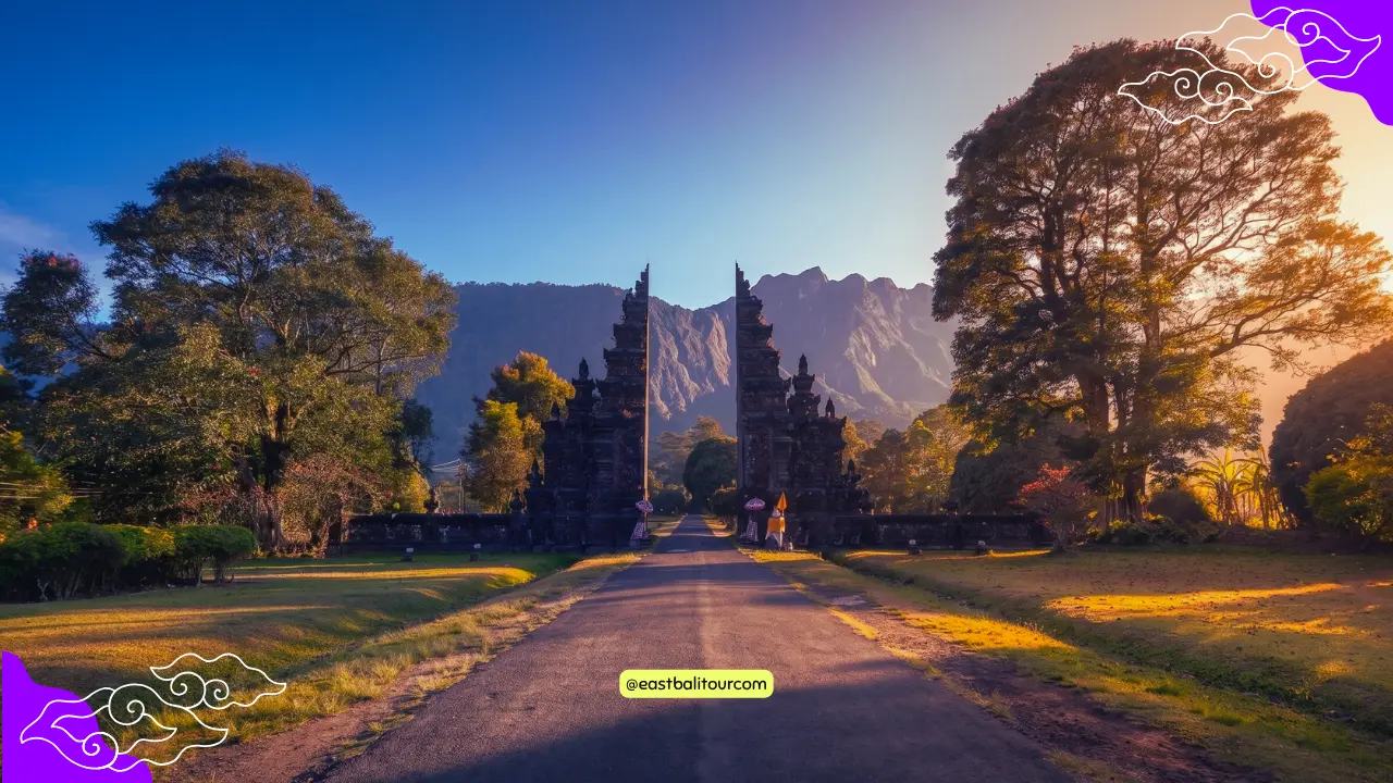 El tiempo en Bali: Una carretera rodeada de palmeras tropicales con el majestuoso Monte Agung al fondo bajo un cielo despejado.