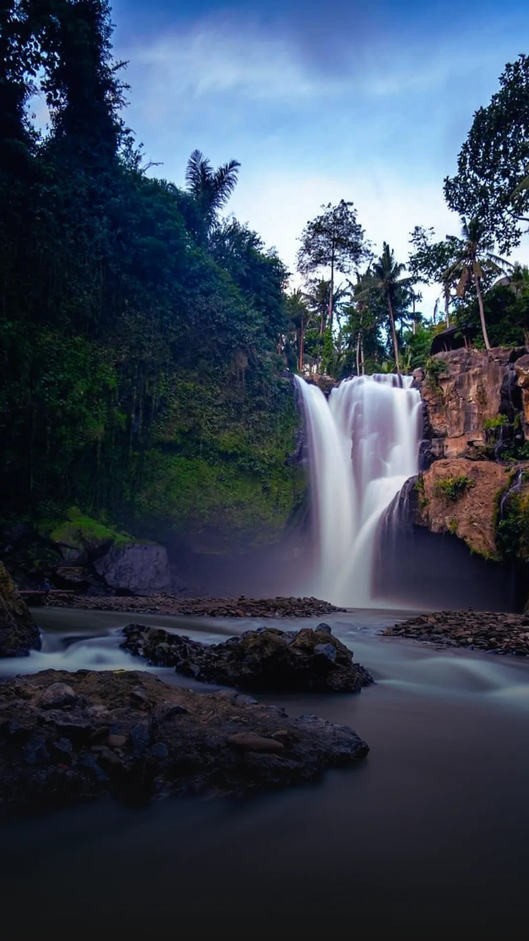 Powerful cascade of Tegenungan Waterfall rushing over a cliff into a tropical jungle plunge pool in Gianyar, Bali.