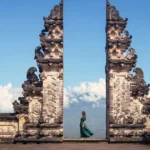 Woman in an elegant red dress walking down the central stone pathway at Lempuyang Temple overlooking Mount Agung.