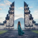 Tourist posing between the candi bentar split gates at Lempuyang Temple during sunrise.