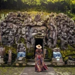 Ancient stone cave entrance overgrown with roots at Goa Gajah in Bali